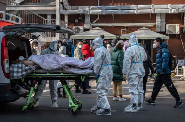 Nhân viên y tế mặc đồ bảo hộ khi đến đón một bệnh nhân nằm trên cáng tại một phòng khám sốt ở Bắc Kinh, hôm 09/12/2022. (Ảnh: Kevin Frayer/Getty Images)