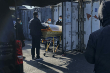 Một linh cữu được hạ xuống từ ​​xe tang và đưa vào một container bảo quản lạnh tại nhà tang lễ và nhà hỏa táng Đông Giao, một trong số những cơ sở được chỉ định giải quyết các ca nhiễm COVID-19 ở Bắc Kinh, Trung Quốc, hôm 18/12/2022. (Ảnh: Getty Images)