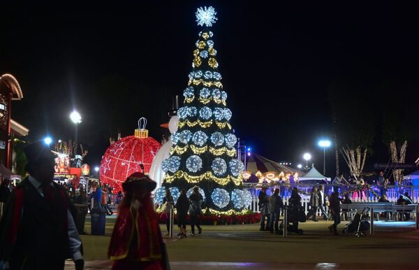 Mọi người đi ngang qua cây thông Noel được thắp sáng tại Lễ hội mùa đông ở Costa Mesa, California, hôm 19/12/2016. (Ảnh: Frederic J. Brown/AFP qua Getty Images)