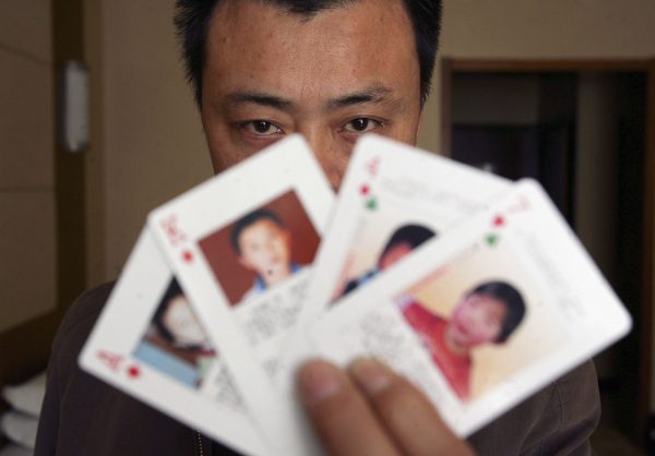 Ông Thẩm Hạo (Shen Hao), người sáng lập trang web tìm người mất tích XRQS.com, đang xòe những lá bài “có hình ảnh những đứa trẻ mất tích,” ở Bắc Kinh, Trung Quốc, vào ngày 31/03/2007. (Ảnh: China Photos/Getty Images)