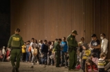 Các nhân viên Tuần tra Biên giới Hoa Kỳ kiểm tra giấy tờ tùy thân của những người nhập cư khi họ chờ được giải quyết sau khi băng qua biên giới từ Mexico ở Yuma, Arizona, hôm 22/06/2022. (Ảnh: Qian Weizhong/VCG/Getty Images)