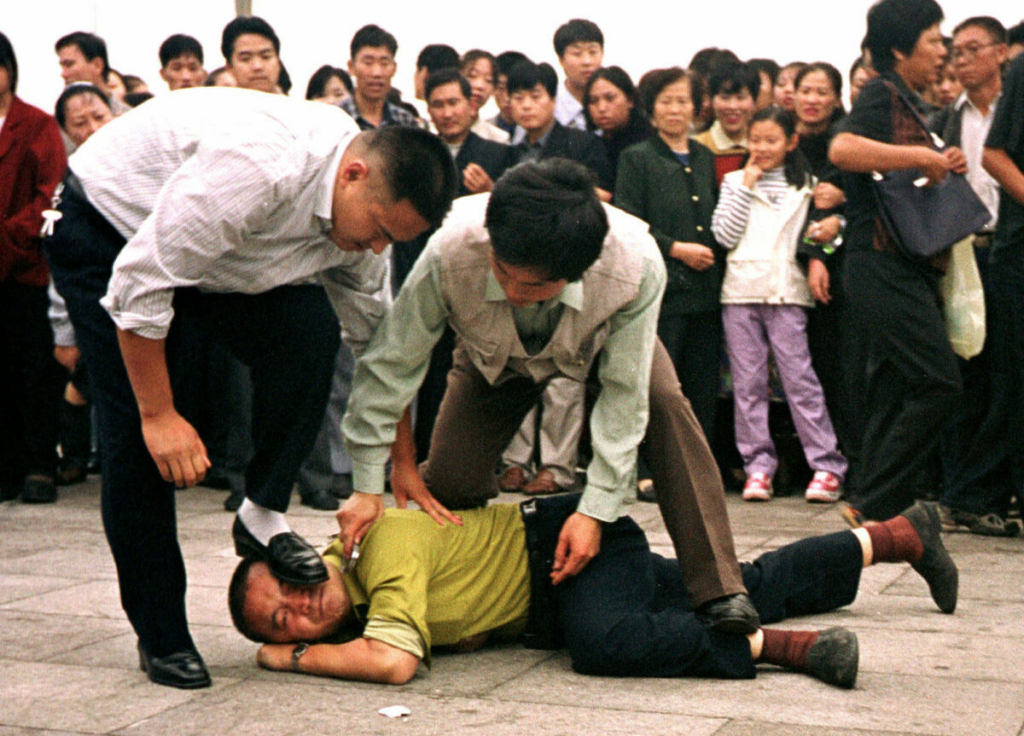 Hai công an mặc thường phục bắt giữ một học viên Pháp Luân Công tại Quảng trường Thiên An Môn ở Bắc Kinh, vào ngày 31/12/2000. (Ảnh: AP Photo/Chien-min Chung)