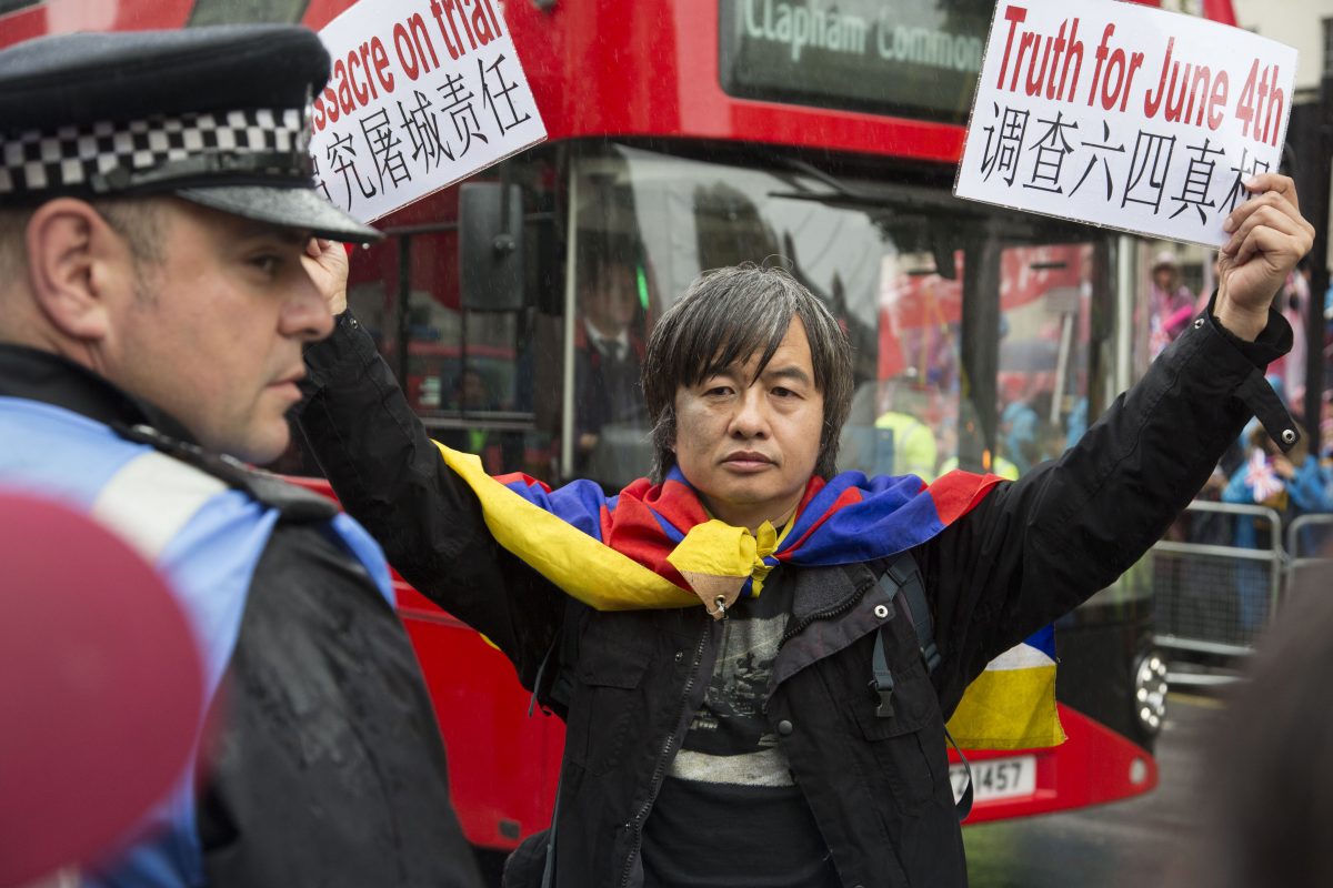 Người sống sót sau vụ thảo sát ở Quảng trường Thiên An Môn kiêm nhà hoạt động dân chủ Thiệu Giang (Shao Jiang) cầm biểu ngữ trước khi bị bắt trong chuyến thăm cấp nhà nước của lãnh đạo Trung Quốc Tập Cận Bình tại London, vào ngày 21/10/2015. (Ảnh: Si Gross/Epoch Times)