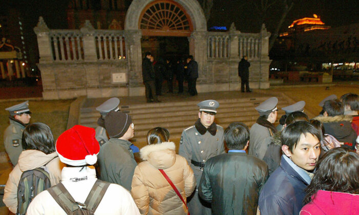 Nhân viên an ninh cùng cảnh sát Trung Quốc đứng chặn hàng trăm tín đồ Cơ Đốc Giáo không cho đến gần Nhà thờ Công Giáo Vương Phủ Tỉnh trong lễ Giáng Sinh ở Bắc Kinh, Trung Quốc, ngày 25/12/2003. (Ảnh: Goh Chai Hin/AFP qua Getty Images)