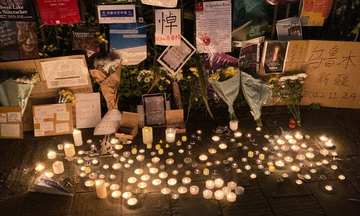 Sau khi một vụ cháy chung cư ở khu vực Tân Cương của Trung Quốc làm ít nhất 10 người thiệt mạng, người ta thấy những tấm bảng và nến trong một buổi lễ tưởng niệm tại Đại học Cambridge, Anh, hôm 29/11/2022. (Ảnh: The Epoch Times)