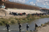 Những người di cư đi bộ qua sông Rio Grande để đầu hàng các nhân viên Tuần tra Biên giới Hoa Kỳ ở El Paso, Texas, nhìn từ Ciudad Juarez, tiểu bang Chihuahua, Mexico, hôm 13/12/2022. (Ảnh: Herika Martinez/AFP/Getty Images)