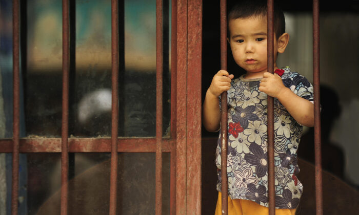 Một cậu bé người Duy Ngô Nhĩ nhìn ra ngoài từ ngôi nhà của mình ở khu vực người Duy Ngô Nhĩ ở thành phố Urumqi thuộc vùng Tân Cương, Trung Quốc vào ngày 12/07/2009. (Ảnh: Peter Parks/AFP qua Getty Images)
