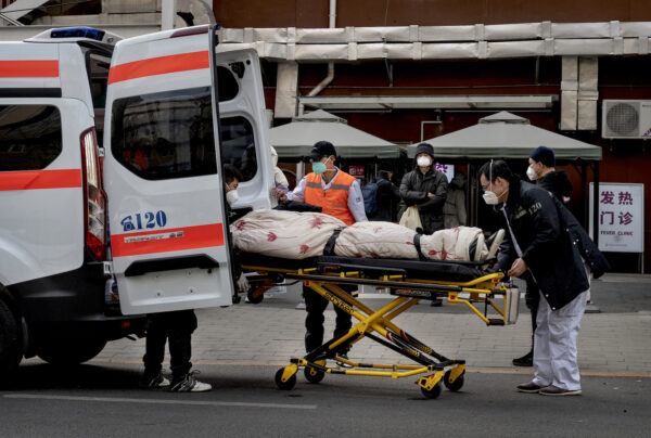 Các lái xe cứu thương đưa một bệnh nhân xuống xe ở bên ngoài một phòng khám điều trị COVID-19 tại Bắc Kinh hôm 21/12/2022. (Ảnh: Kevin Frayer/Getty Images)