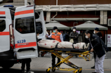 Tài xế xe cứu thương mở cửa sau đưa bệnh nhân cấp cứu ra ngoài, ở phía trước phòng khám điều trị bệnh nhân COVID-19 tại Bắc Kinh hôm 21/12/2022. (Ảnh: Kevin Frayer/Getty Images)