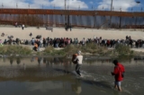 Những người nhập cư bất hợp pháp đi qua sông Rio Grande để đầu hàng các nhân viên Lực lượng Tuần tra Biên giới Hoa Kỳ ở El Paso, Texas, nhìn từ Ciudad Juarez, tiểu bang Chihuahua, Mexico, hôm 13/12/2022. (Ảnh: Herika Martine/AFP via Getty Images)