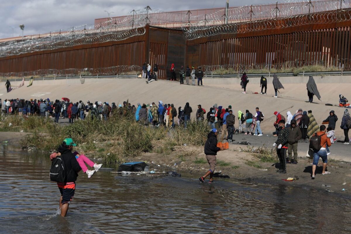 Những người nhập cư bất hợp pháp đi bộ qua Rio Grande để đầu hàng các nhân viên của Lực lượng Tuần tra Biên giới Hoa Kỳ ở El Paso, Texas, nhìn từ Ciudad Juarez, tiểu bang Chihuahua, Mexico, hôm 13/12/2022. (Ảnh: Herika Martinez/AFP qua Getty Images)