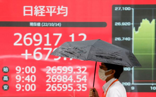 Một người đàn ông đi ngang qua một màn hình điện tử hiển thị mức trung bình cổ phiếu Nikkei của Nhật Bản ở Tokyo hôm 14/10/2022. (Ảnh: Issei Kato/Reuters)