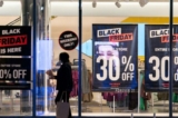 Một người phụ nữ đi ngang qua các biển quảng cáo giảm giá Black Friday ở quận Manhattan của Thành phố New York, New York, hôm 26/11/2021. (Ảnh: Jeenah Moon/Reuters)