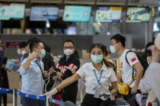 Một nhân viên hàng không hướng dẫn du khách Trung Quốc xếp hàng để lấy số ghế ngồi trên chuyến bay đến Vũ Hán tại phi trường Suvarnabhumi, Bangkok, Thái Lan, vào ngày 31/01/2020. (Ảnh: Gemunu Amarasinghe/AP)