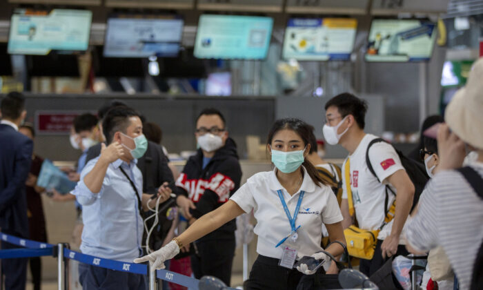 Một nhân viên hàng không hướng dẫn du khách Trung Quốc xếp hàng để lấy số ghế ngồi trên chuyến bay đến Vũ Hán tại phi trường Suvarnabhumi, Bangkok, Thái Lan, vào ngày 31/01/2020. (Ảnh: Gemunu Amarasinghe/AP)