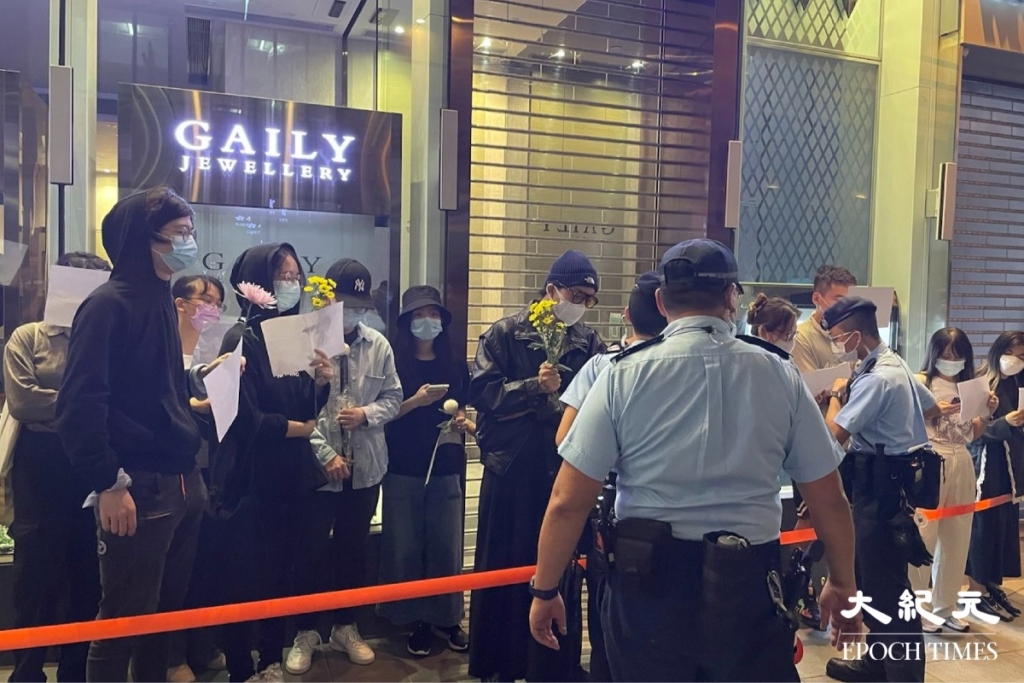 Vào tối hôm 28/11/2022, một số sinh viên và công dân từ Trung Quốc đại lục ở Hồng Kông đã tổ chức flash mob tại Nhà hát Trung tâm để ủng hộ “Cuộc biểu tình Giấy Trắng” ở Trung Quốc đại lục. Cảnh sát đã bao vây những người biểu tình và ghi lại thông tin cá nhân của họ. (Ảnh: Cheuk Sheung-yu/The Epoch Times)