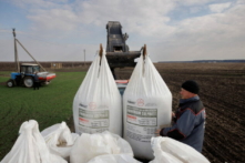 Một công nhân nông trại địa phương bốc dỡ phân bón do Ukraine sản xuất từ ​​một chiếc xe tải để sử dụng trên cánh đồng lúa mì gần làng Yakovlivka sau khi nơi này bị trúng bom từ trên không bên ngoài Kharkiv, Ukraine, hôm 05/04/2022. (Ảnh: Thomas Peter/Reuters)