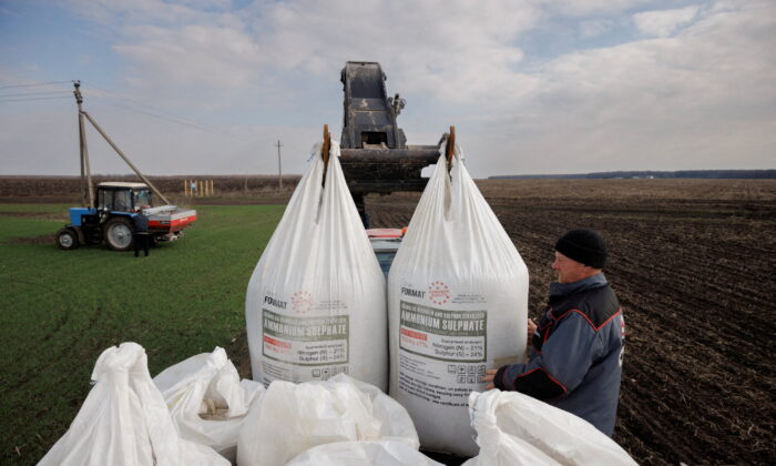 Một công nhân nông trại địa phương bốc dỡ phân bón do Ukraine sản xuất từ ​​một chiếc xe tải để sử dụng trên cánh đồng lúa mì gần làng Yakovlivka sau khi nơi này bị trúng bom từ trên không bên ngoài Kharkiv, Ukraine, hôm 05/04/2022. (Ảnh: Thomas Peter/Reuters)