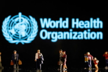 Những bức tượng nhỏ được nhìn thấy ở phía trước logo của Tổ chức Y tế Thế giới trong hình minh họa chụp ngày 11/02/2022 này. (Ảnh: Dado Ruvic/Reuters)