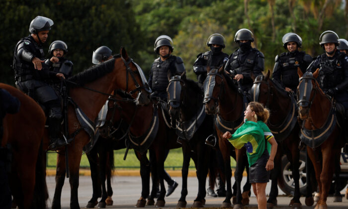 Một người biểu tình phản ứng bên cạnh các thành viên của lực lượng an ninh khi những người ủng hộ cựu Tổng thống Brazil Jair Bolsonaro rời một khu lều trại bên ngoài Trụ sở Quân đội, ở Brasilia, Brazil, hôm 09/01/2023. (Ảnh: Amanda Perobelli/Reuters)