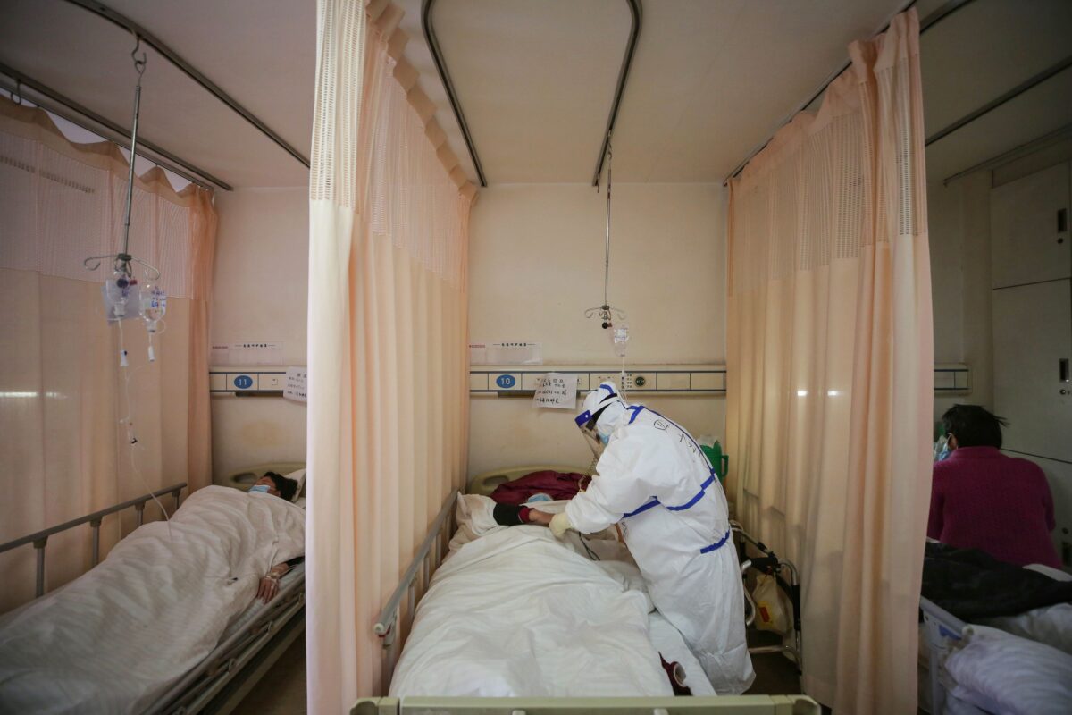 Một nhân viên y tế điều trị cho một bệnh nhân bị nhiễm virus corona COVID-19 tại Bệnh viện Chữ thập Đỏ ở Vũ Hán thuộc tỉnh Hồ Bắc, miền trung Trung Quốc hôm 11/03/2020. (Ảnh: STR/AFP/Getty Images)