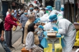 Các nhân viên y tế lấy mẫu bệnh phẩm từ người dân để xét nghiệm virus corona COVID-19, trên một con đường ở Vũ Hán, trung tâm tỉnh Hồ Bắc của Trung Quốc, hôm 15/05/2020. (Ảnh: STR/AFP/Getty Images)
