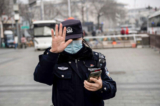 Một sĩ quan cảnh sát ra hiệu cho một ký giả không được chụp hình ở Bắc Kinh, Trung Quốc, hôm 05/03/2021. (Ảnh: Nicolas Asfouri/AFP qua Getty Images)