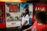Người dân đi ngang qua một tấm bích chương quảng cáo lịch chiếu phim ‘1921’, một bộ phim tuyên truyền về sự ra đời của Đảng Cộng sản Trung Quốc cùng năm đó, trước thềm lễ kỷ niệm 100 năm thành lập Đảng Cộng sản Trung Quốc tại một rạp chiếu phim ở Bắc Kinh vào ngày 28/06/2021. (Ảnh: Wang Zhao/AFP qua Getty Images)