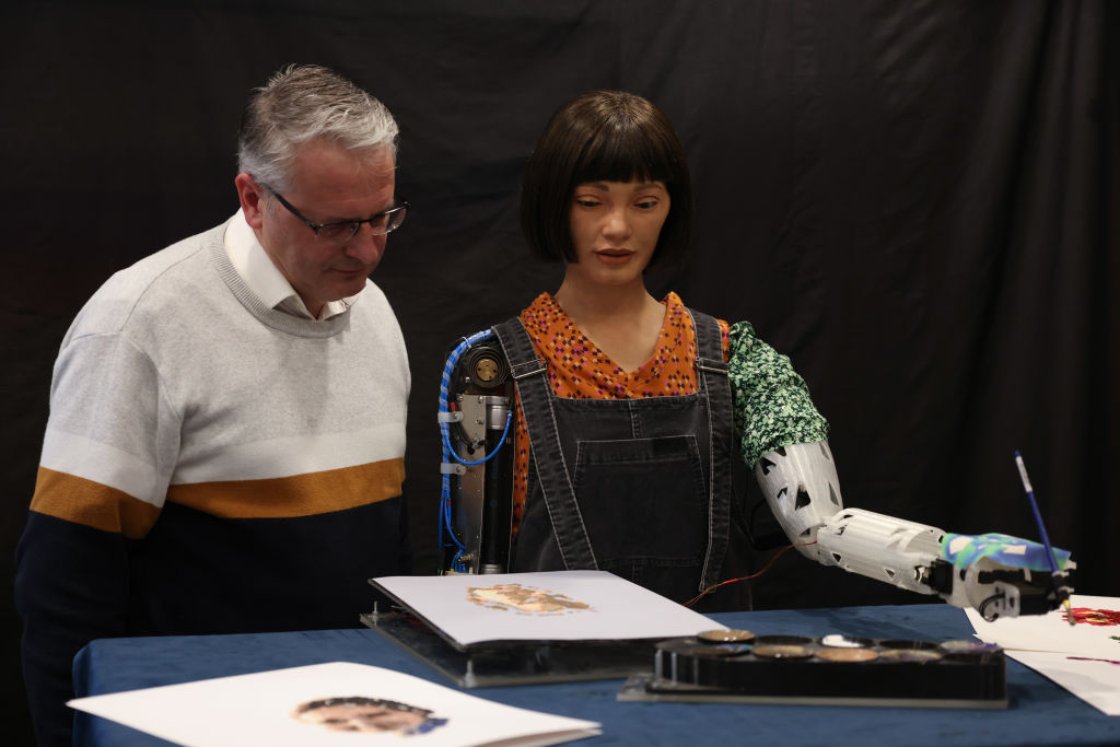 Ông Aidan Meller xem một bức tranh của Ai-Da Robot, một nghệ sĩ robot hình người siêu thực, trong cuộc họp báo tại Thư viện Anh ở London, Anh, hôm 04/04/2022. (Hollie Adams/Getty Images)