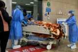Nhân viên y tế di chuyển một bệnh nhân COVID-19 trên băng ca cứu thương trong khu cấp cứu của Bệnh viện Trực thuộc Số 1 thuộc Đại học Y Trùng Khánh ở thành phố Trùng Khánh phía tây nam Trung Quốc hôm 22/12/2022. (Ảnh: Noel Celis/AFP qua Getty Images)