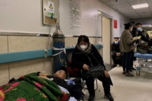 Một bệnh nhân nhiễm COVID-19 nằm trên giường ở hành lang tại Bệnh viện Công nhân Đường Sơn ở thành phố Đường Sơn, đông bắc Trung Quốc hôm 30/12/2022. (Ảnh: Noel Celis/AFP qua Getty Images)