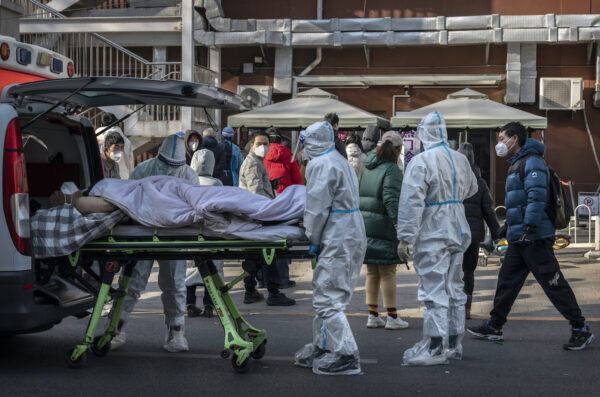 Nhân viên y tế mặc đồ bảo hộ khi họ đưa một bệnh nhân nằm trên băng ca đến một phòng khám sốt ở Bắc Kinh hôm 09/12/2022. (Ảnh: Kevin Frayer/Getty Images)