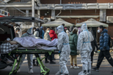 Nhân viên y tế mặc bộ đồ bảo hộ khi đến một phòng khám sốt với một bệnh nhân nằm trên cáng hôm 09/12/2022 tại Bắc Kinh, Trung Quốc. (Ảnh: Kevin Frayer/Getty Images)