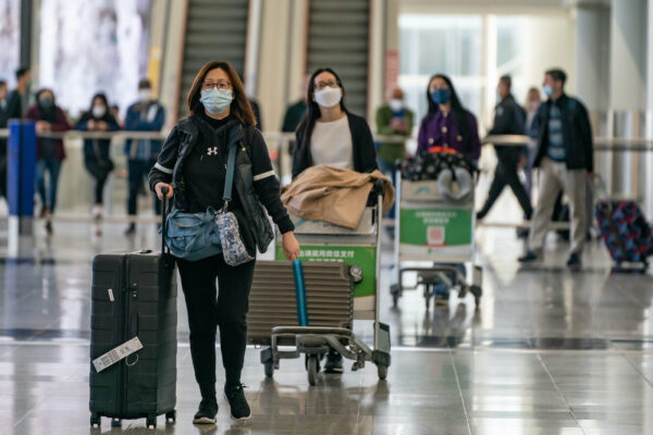 Du khách mang theo hành lý bước đi tại sảnh đến của Phi trường Quốc tế Hồng Kông hôm 30/12/2022. (Ảnh: Anthony Kwan/Getty Images)