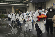 Một người đưa tang khiêng di hài hỏa táng của người thân trong khi ông và những người khác mặc trang phục tang lễ màu trắng truyền thống, trong một đám tang ở Thượng Hải. (Ảnh: Kevin Frayer/Hình ảnh Getty)