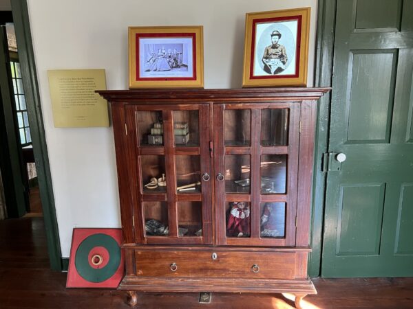 “Trạm trò chơi” của gia đình Grant vào những năm 1800 là một tủ cửa kính, chẳng hạn như tủ đồ cổ bằng gỗ gụ này, được đặt trong phòng khách và chứa đầy các trò chơi phổ biến như chơi bi, chơi bài, tung vòng, domino, v.v. Những cuốn sách cũng được đặt trong tủ gỗ nguyên khối này. Những bức ảnh gia đình thường được trang trí trên bề mặt đồ nội thất, chẳng hạn như ảnh của bà Julia chụp cùng mẹ, cha, và anh trai của bà, cũng như ảnh của bà Grant khi còn là một sĩ quan tiếp tế trẻ ở Lục quân. (Ảnh: Cục Công viên Quốc gia)