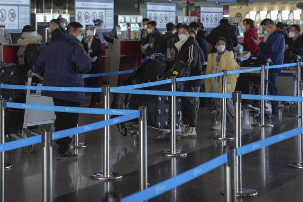 Những du khách đeo khẩu trang xếp hành lý tại quầy làm thủ tục chuyến bay quốc tế tại Phi trường Quốc tế Thủ đô Bắc Kinh, Trung Quốc hôm 29/12/2022. (Ảnh: Andy Wong/AP Photo)