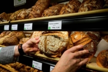 Một thợ làm bánh người Đức đặt những ổ bánh mì lên kệ trưng bày tại một tiệm bánh ở Berlin hôm 28/12/2022. (Ảnh: John Macdougall/AFP qua Getty Images)