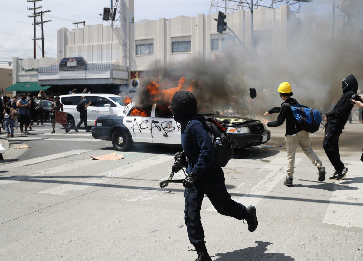 Một chiếc xe của Sở Cảnh sát Los Angeles (LAPD) bị những người bạo loạn phóng hỏa ở Los Angeles, California, vào ngày 30/05/2020. (Ảnh: Mario Tama/Getty Images)