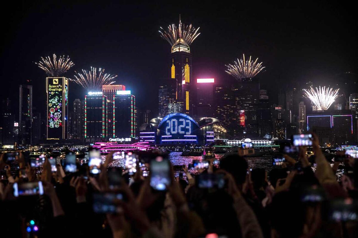 Người dân xem màn trình diễn pháo hoa và laser khi họ đón mừng Năm Mới bên cạnh Cảng Victoria ở Hồng Kông hôm 01/01/2023. (Ảnh: Isaac Lawrence/AFP qua Getty Images)