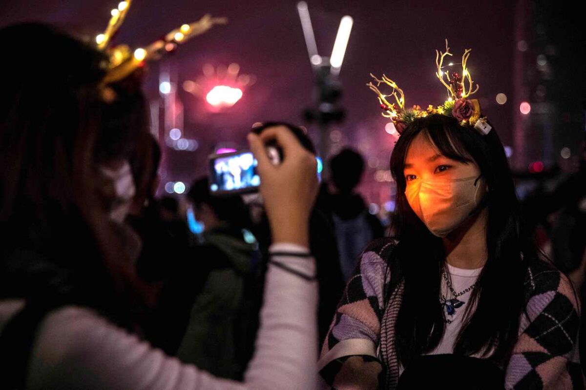Người đi vui chơi chụp ảnh trong màn trình diễn pháo hoa và laser khi đón mừng Năm Mới bên cạnh Cảng Victoria ở Hồng Kông hôm 01/01/2023. (Ảnh: Isaac Lawrence/AFP qua Getty Images)