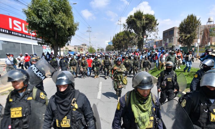 Các thành viên của cảnh sát hộ tống những người ủng hộ cựu Tổng thống Pedro Castillo trong khi họ diễu hành đến trung tâm thành phố Arequipa, Peru, yêu cầu đóng cửa Quốc hội và trả tự do cho ông Castillo, hôm 14/12/2022. (Ảnh: Diego Ramos/AFP qua Getty Images)