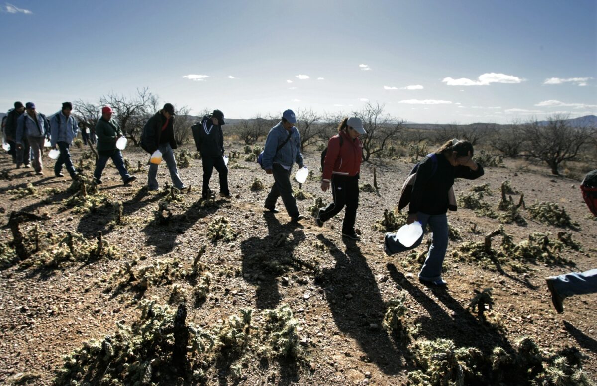 Mang theo những bình nước chứa được nhiều gallon, những người di cư đi bộ dọc theo các lối đi ở phía bắc biên giới Mexico-Arizona. (Ảnh: Don Bartletti/Los Angeles Times)