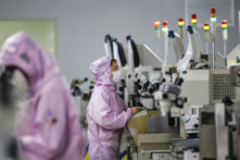 Công nhân Trung Quốc đeo khẩu trang và mặc đồ bảo hộ làm việc trên dây chuyền sản xuất vi mạch bán dẫn thông minh ở huyện Tứ Hồng (Sihong), tỉnh Giang Tô, miền đông Trung Quốc vào ngày 16/02/2020. (Ảnh: STR/AFP)