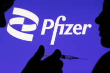 Một người cầm ống chích tạo dáng trước logo Pfizer Inc. vào ngày 11/12/2021. (Ảnh: Dado Ruvic/Reuters)