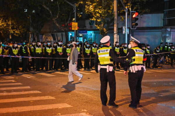 Các sĩ quan cảnh sát phong tỏa Đường Ô Lỗ Mộc Tề (Wulumuqi Street) ở Thượng Hải, nơi diễn ra các cuộc biểu tình phản đối quy định zero COVID vào đêm hôm trước để phản ứng với vụ hỏa hoạn gây thiệt mạng ở Unumqi, Tân Cương, vào ngày 27/11/2022. (Ảnh: Hector Retamal/AFP qua Getty Images)