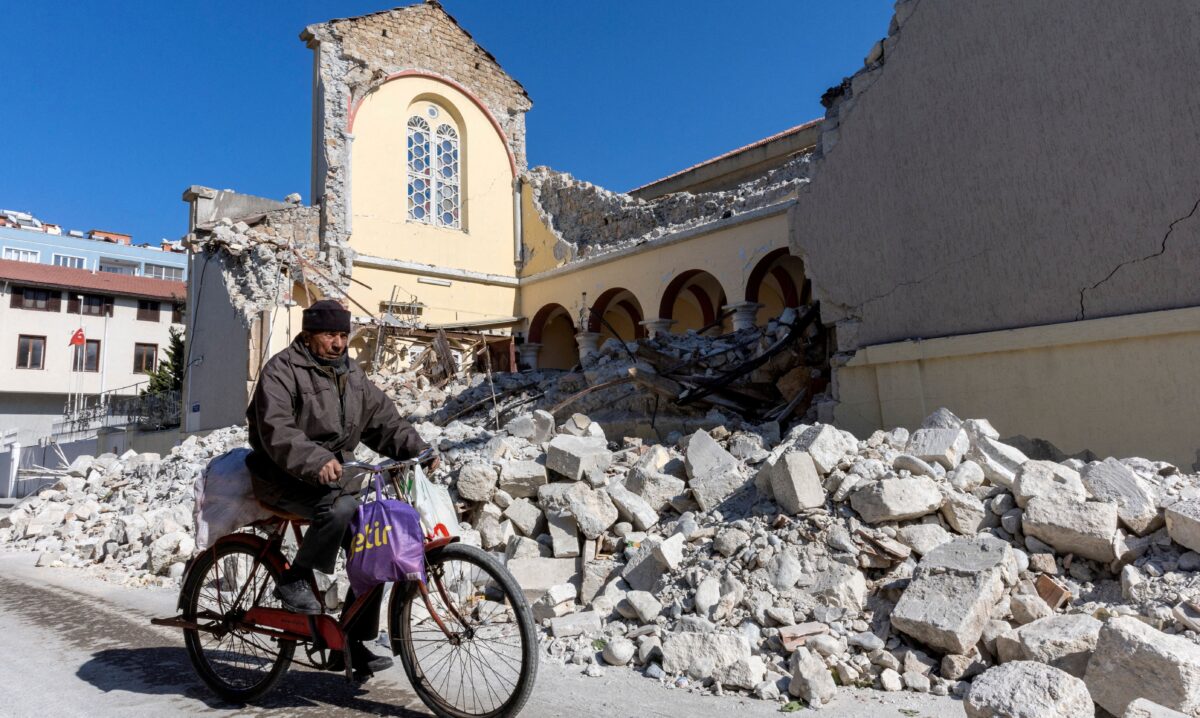 Một người đàn ông đạp xe dọc theo một nhà thờ Công giáo La Mã bị sập sau trận động đất gây thương vong lớn ở Iskenderun, một thị trấn ven biển của tỉnh Hatay, Thổ Nhĩ Kỳ, hôm 14/02/2023. (Ảnh: Umit Bektas/Reuters)