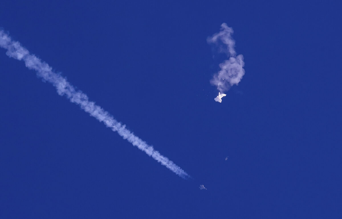 Những phần còn lại của một khí cầu lớn trôi dạt phía trên Đại Tây Dương, ngay ngoài khơi bờ biển South Carolina, với một chiến đấu cơ cùng vệt trắng đằng sau, hôm 04/02/2023. (Ảnh: Chad Fish qua AP)