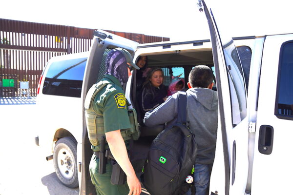 Một nhân viên Tuần tra Biên giới Hoa Kỳ đưa một gia đình ba người từ Columbia lên một chiếc xe để đến một cơ sở xét xử liên bang hôm 27/01/2023. (Ảnh: Allan Stein/The Epoch Times)