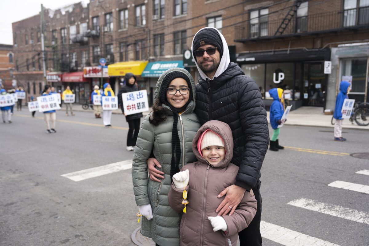 Anh Miguel Garcia và gia đình xem các học viên Pháp Luân Công tuần hành trong một cuộc diễu hành ở Brooklyn, New York, nêu bật cuộc đàn áp đối với đức tin của họ ở Trung Quốc, hôm 26/02/2023. (Ảnh: Chung I Ho/The Epoch Times)